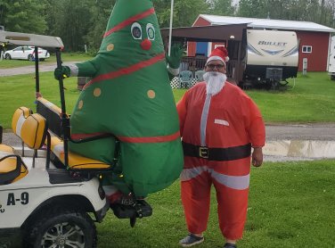 Santa standing next to blow up X mass tree