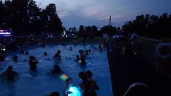 People in the pool with glow items at night