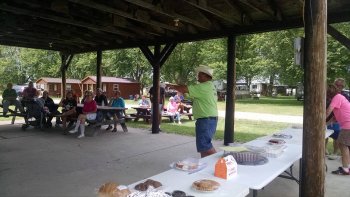 Man in green shirt auctioning off items to camper at The Ridge Campground